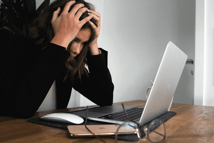 Femme devant un ordinateur se tenant la tête