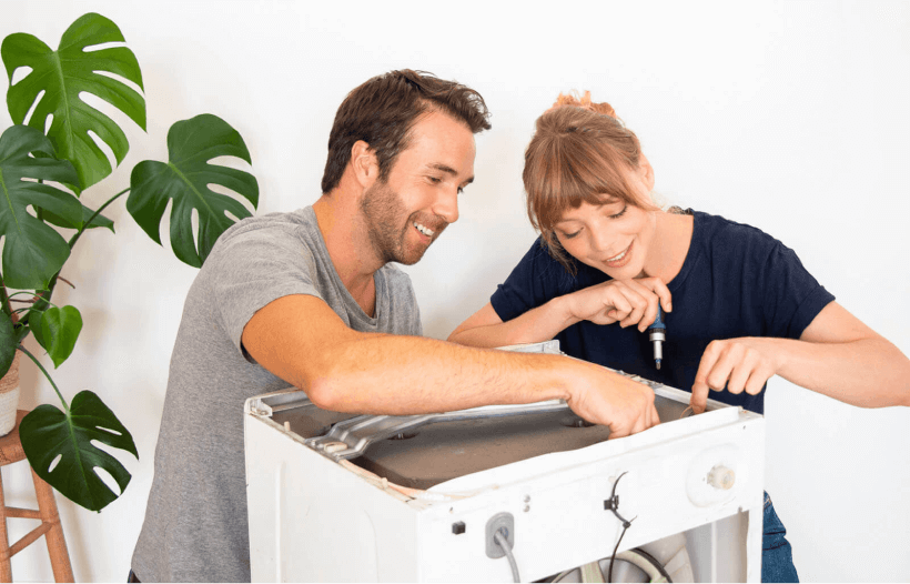 Un homme et une femme en train de réparer une machine à laver.