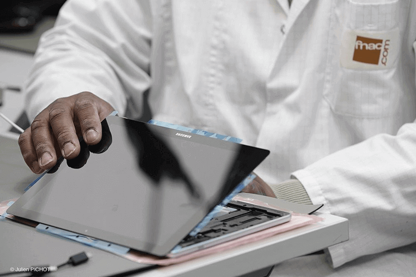 Technicien Fnac reconditionnant une tablette.