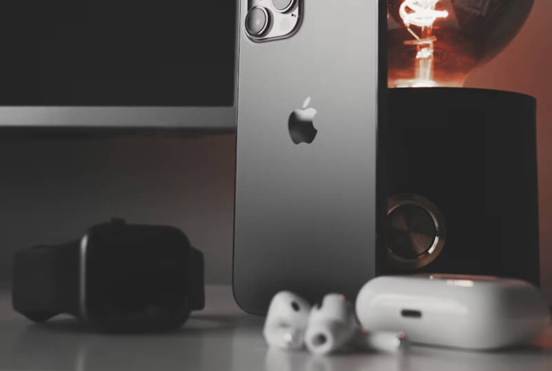 iPhone 12 Pro posé à côté d'AirPods, illustrant la connectivité audio de l'appareil et son système de haut-parleurs stéréo intégré pour la consommation de contenu.