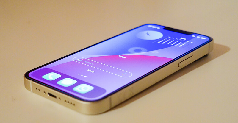 iPhone 13 mini avec écran allumé affichant une interface colorée et lumineuse.