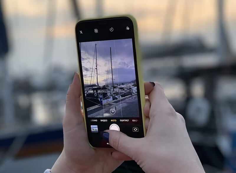 Personne utilisant un iPhone X pour prendre une photo en extérieur.
