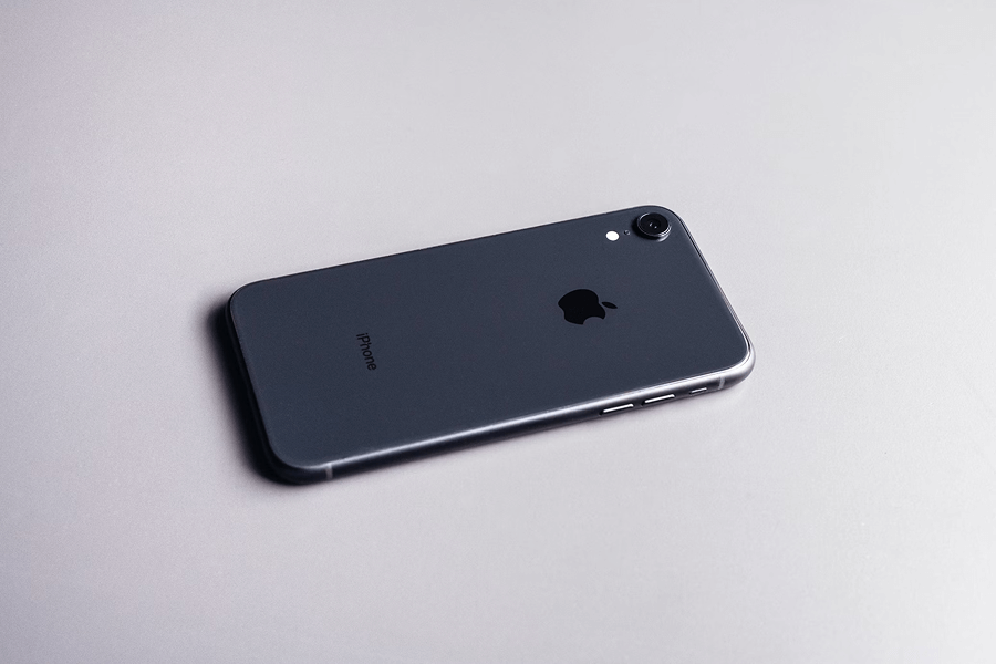 Vue arrière et latérale d'un iPhone XR en couleur, mettant en valeur son dos en verre brillant et sa tranche en aluminium, éléments clés de son design.