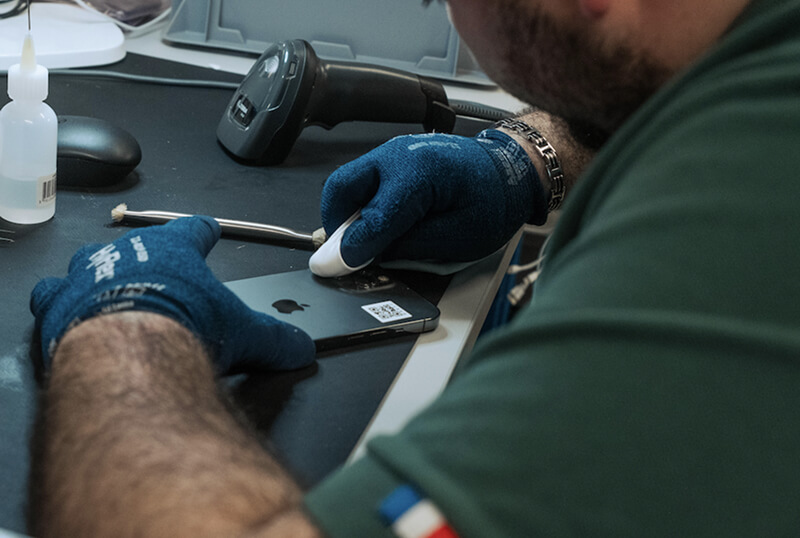 Technicien en train de reconditionner un smartphone dans l'atelier e-Recycle à Lyon