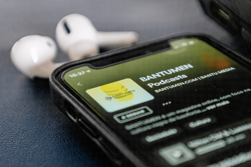 Application Spotify lancée sur un iPhone 12. Airpods en arrière-plan.