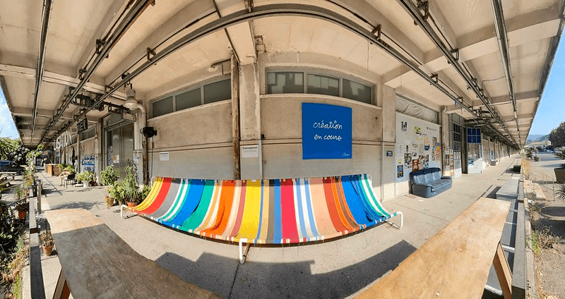 Scène urbaine capturée en mode Panorama avec l’iPhone 12, mettant en évidence une forte distorsion autour d’un banc coloré