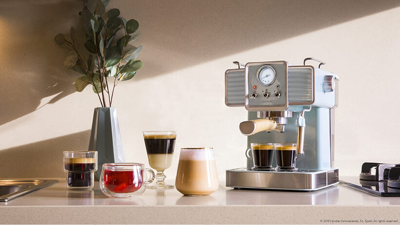 Photo d'une machine Cecotec au design à côté de laquelle se trouve six boissons caféinées.