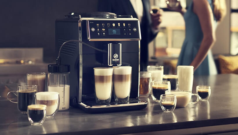 Photo d'une machine à grain Saeco avec mousseur à lait intégré, ainsi qu'une tasse de café latte.