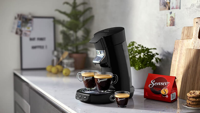 Photo d'une machine Senseo avec deux grandes tasses de café sur le socle et une petite tasse devant la machine.