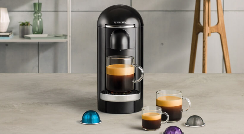 Photo d'une machine Vertuo de Nespresso ainsi que trois tailles de tasses de cafés différentes.