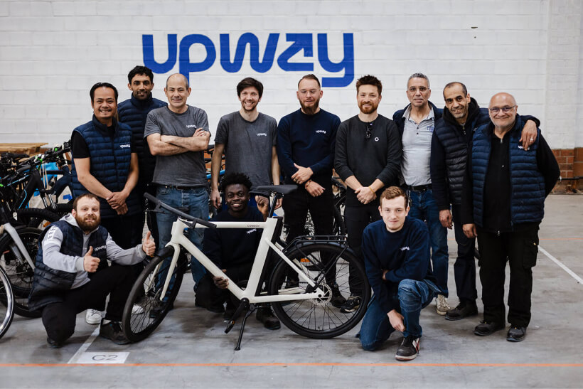 Équipe Upway posant dans leur atelier avec un vélo électrique reconditionné